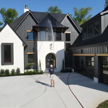 Person pressure washing a modern two-story house's exterior in Wilmington NC, with a long hose leading to a washer on the driveway.