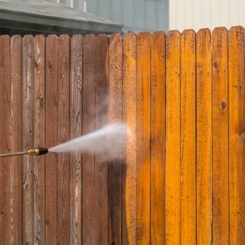Wooden Decks & Fencing Pressure washing a wooden fence, revealing a clean, bright section next to a weathered area; concept of pressure washing Wilmington NC.